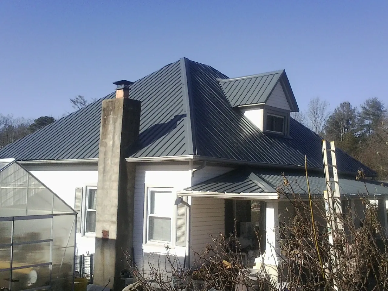 Dark blue standing seam metal roof on a white farmhouse with dormer — Slate & Tile Roof Repair by Roofing Brothers in Los Gatos