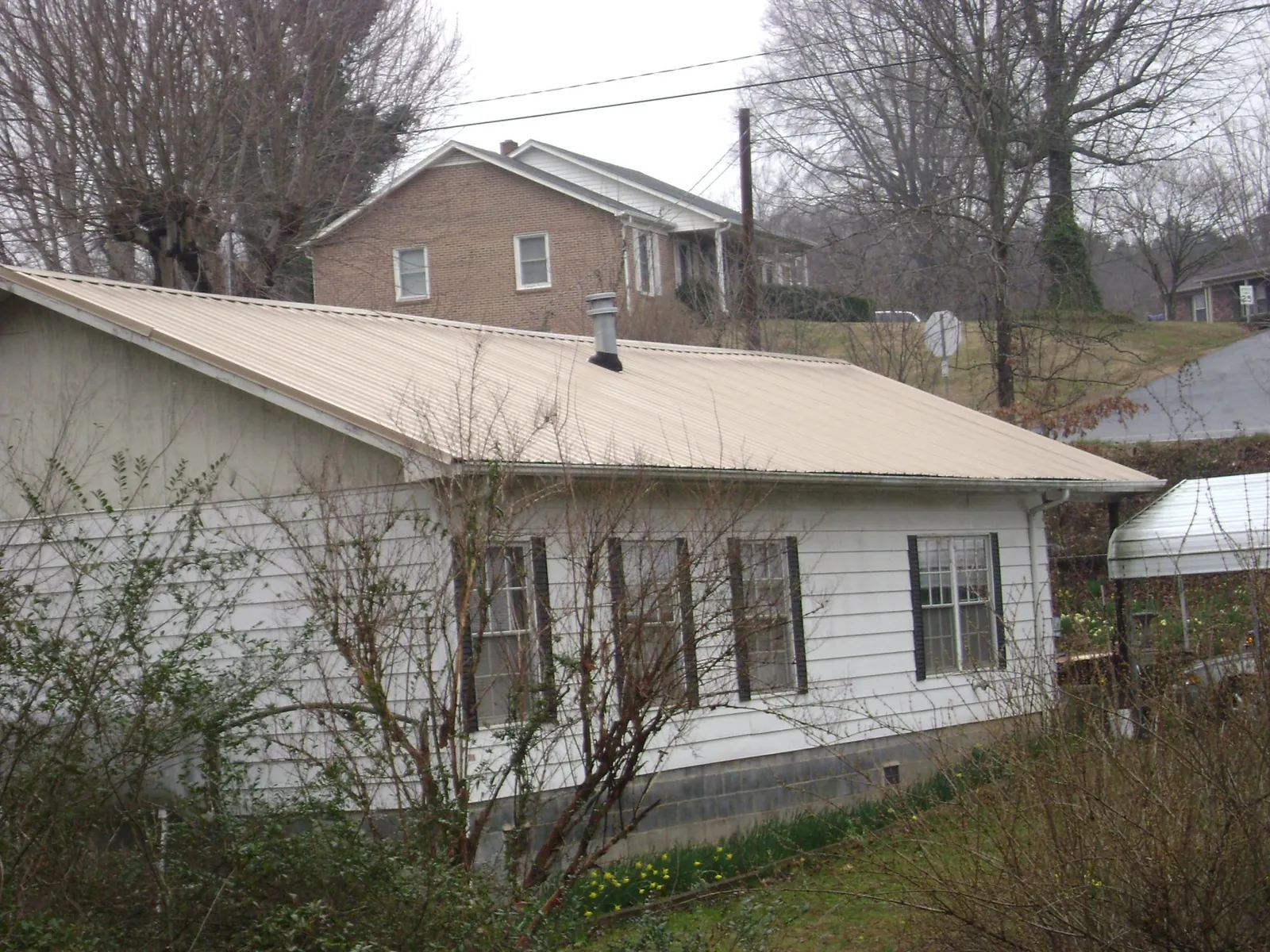 Tan metal roof on a white sided house set into a hillside — Commercial Roofing by Roofing Brothers in Los Gatos