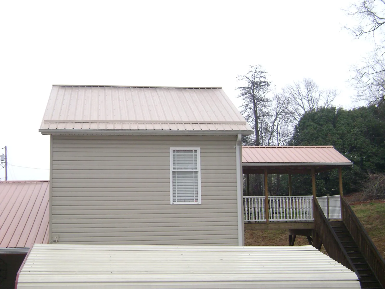 Tan metal roofs on a two story addition and attached porch, from a Roof Replacement job in Los Gatos