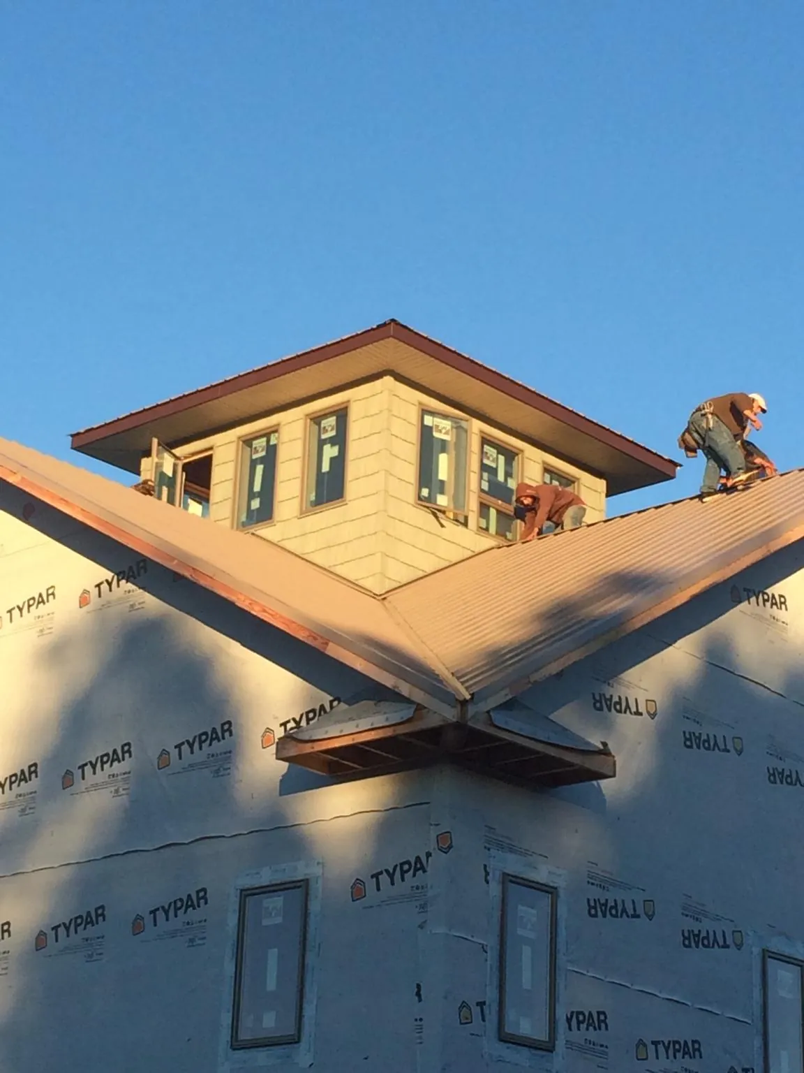 Roofers working around a rooftop cupola on a new metal roof at sunset — Roof Waterproofing in Los Gatos by Roofing Brothers